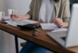 Woman at desk making calculations and notes to support decision.