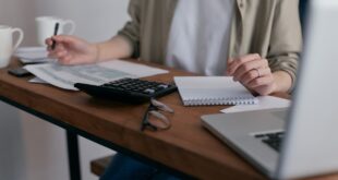 Woman at desk making calculations and notes to support decision.