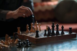 An intense chess match highlighting strategy between a pair of hands and chess pieces on a board.