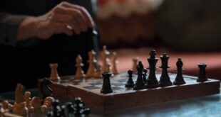 An intense chess match highlighting strategy between a pair of hands and chess pieces on a board.