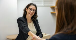 Businesswomen shaking hands in an office, representing a successful job interview or partnership.