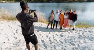 Friends posing by the lake, smiling for a photo together on a sunny day.