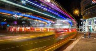Dynamic city street at night captured with vibrant light trails from long exposure photography.