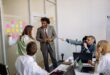 Professionals brainstorming ideas in a conference room with sticky notes and laptops.