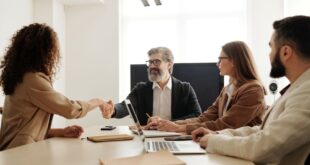 Colleagues in an office celebrating a successful negotiation with a handshake.