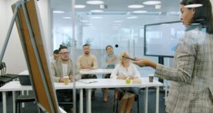 Business team attending a presentation in a glass-walled conference room.